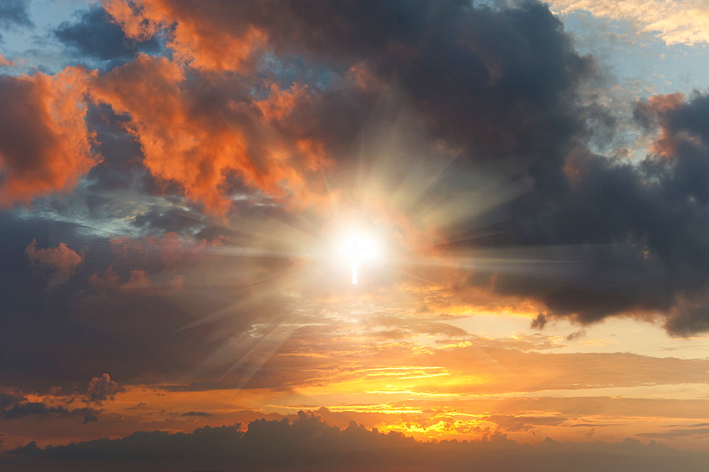 Glowing cross sign in clouds at sunset