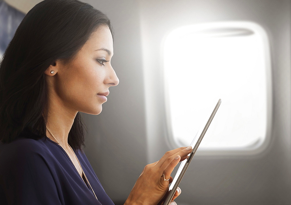 Young woman using tablet on plane