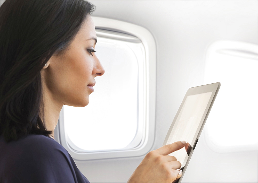 Young woman using tablet on plane