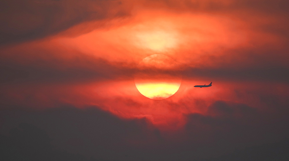 Silhouette of airplane against setting sun