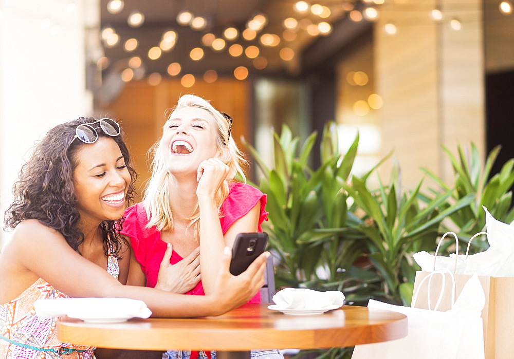 Female friends using smart phone in cafe