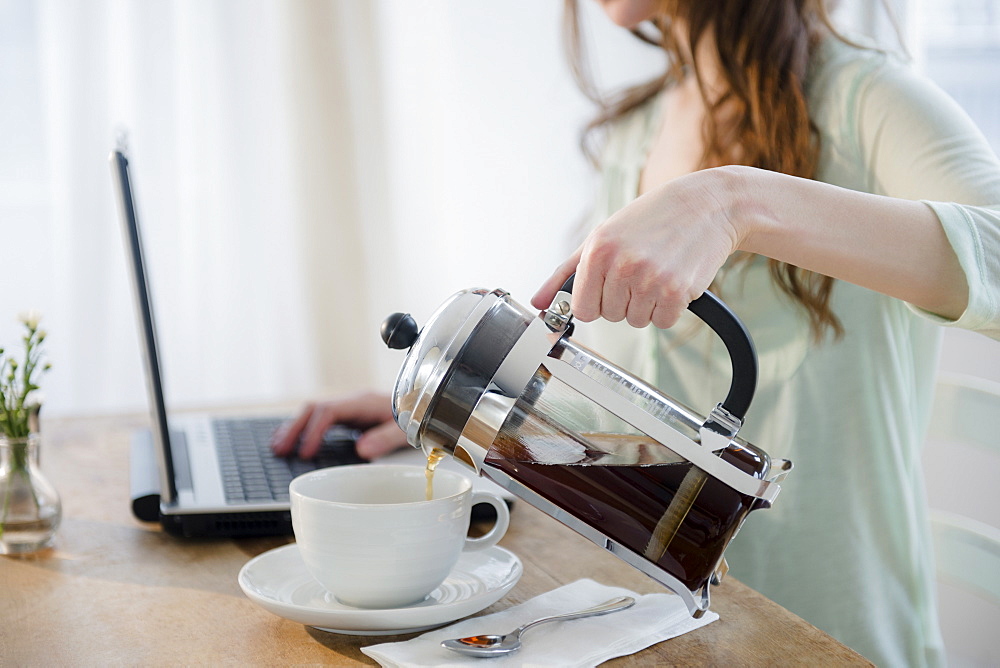 Young woman pouring coffee into cup