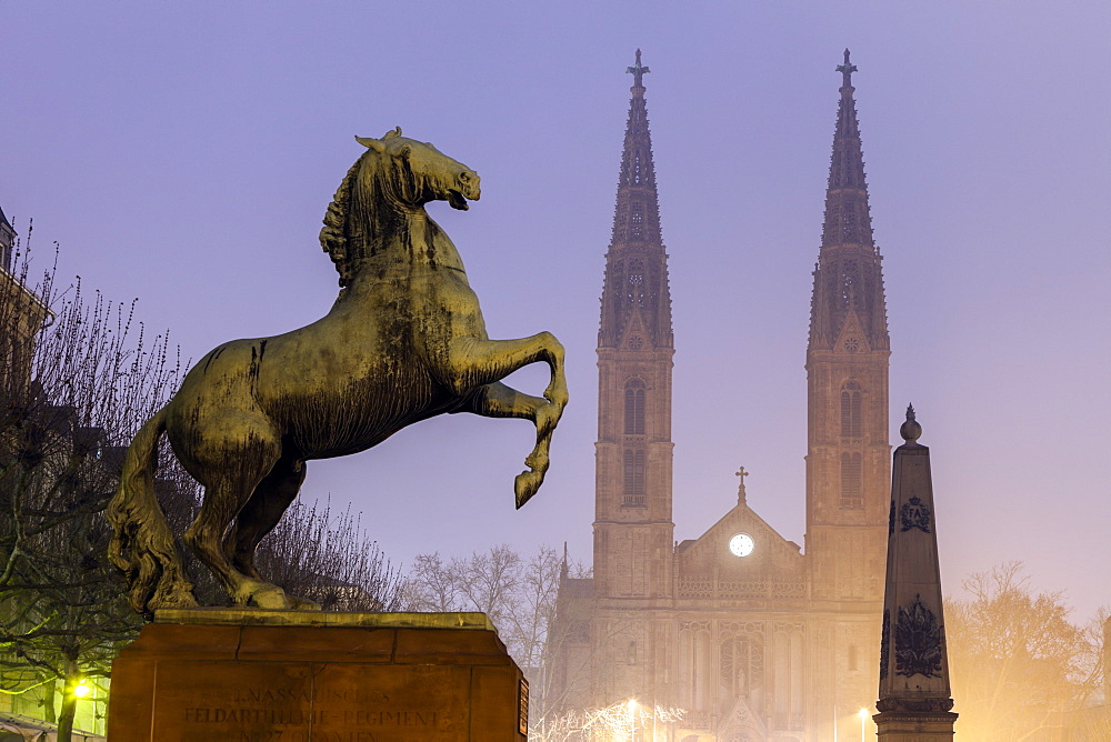 Horse sculpture of Waterloo Memorial and St. Boniface Church in mist, Germany, Hesse, Waterloo Memorial on Luisenplatz, St. Boniface Church