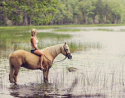 Woman horseback riding in countryside
