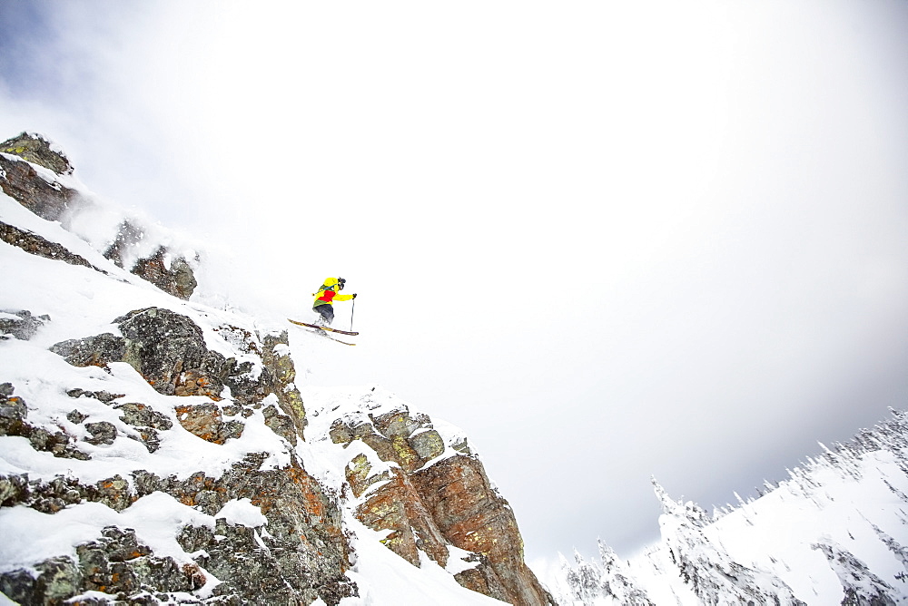 Skier jumping off rocky mountain, USA, Montana, Whitefish