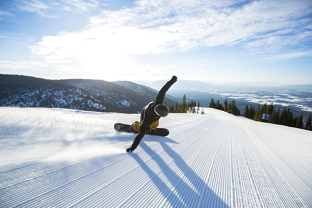 Man snowboarding downhill, USA, Montana, Whitefish