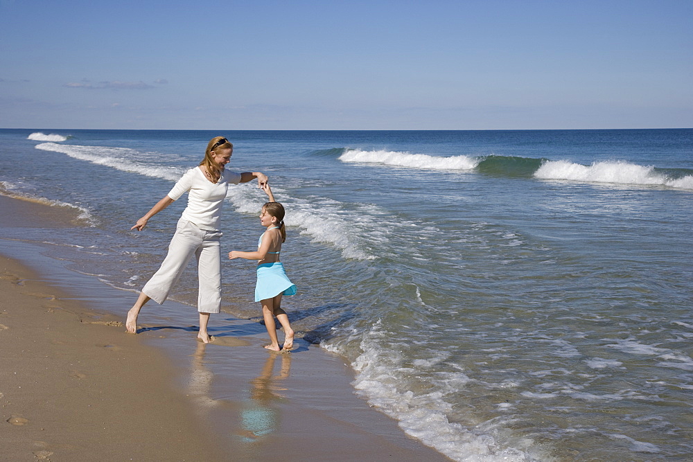 Mother and daughter dancing at beach