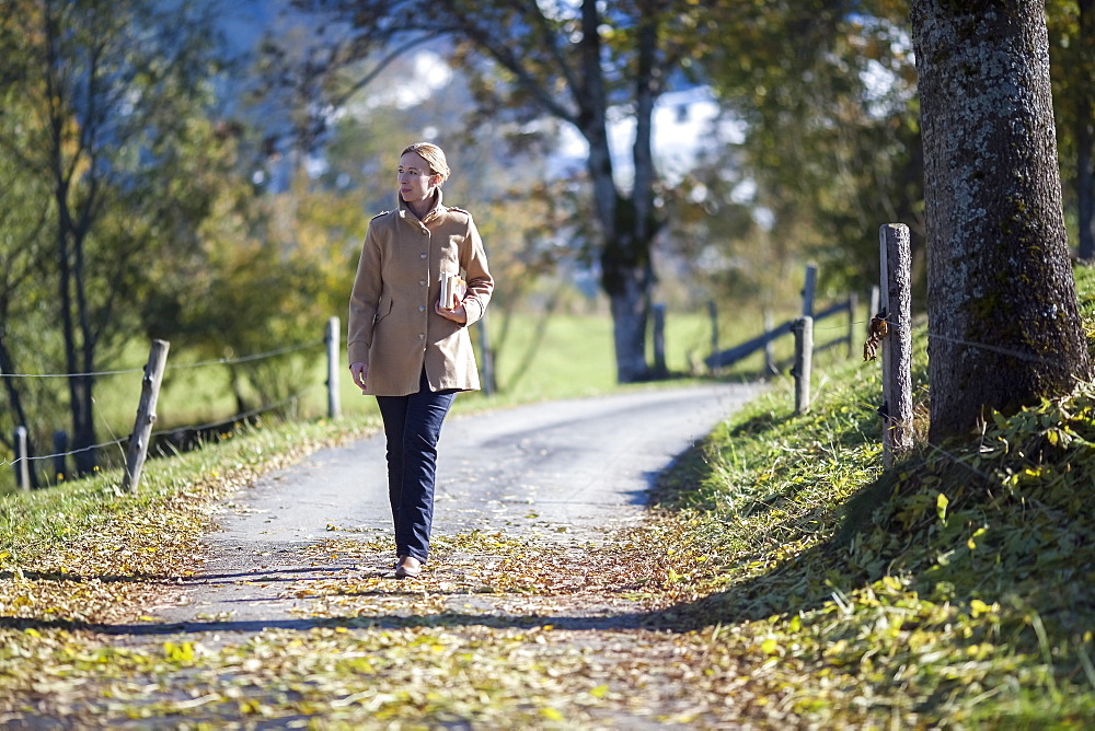 Austria, Salzburger Land, Maria Alm, Mature woman walking on autumn alley