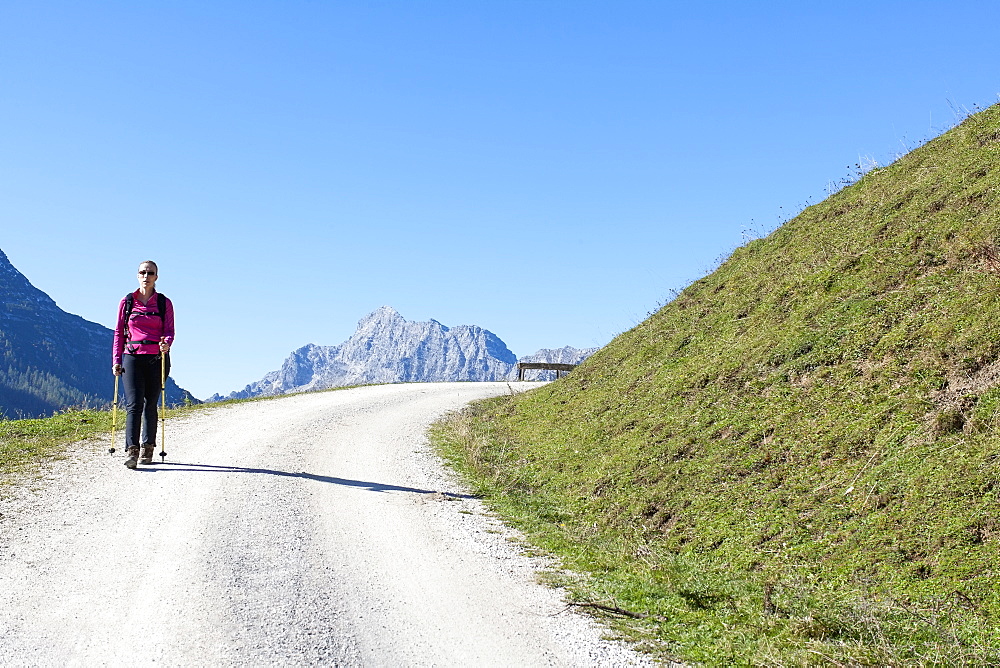 Austria, Salzburger Land, Weissbach, Mature woman hiking on sunny day in mountain landscape