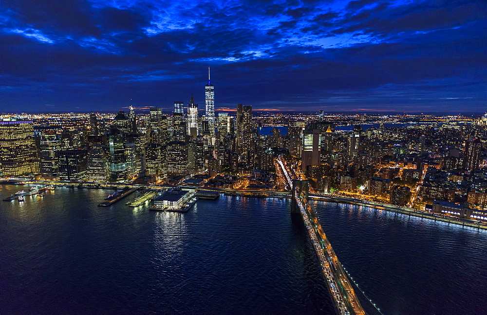 USA, New York, New York City, Manhattan, Aerial view of illuminated skyline with harbor and Brooklyn bridge at night