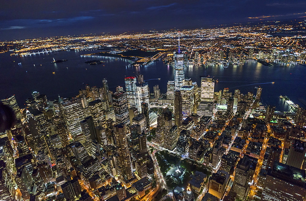 USA, New York, New York City, Manhattan, Aerial view of illuminated skyline with harbor at night