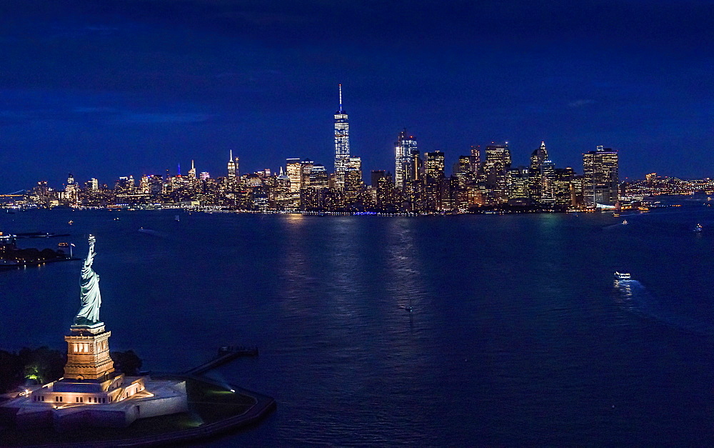 USA, New York, New York City, Manhattan, Aerial view of illuminated skyline with Statue of Liberty at night