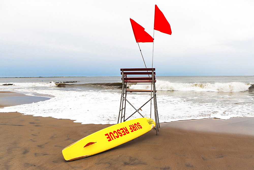 USA, New York State, New York City, Brooklyn, Yellow surfboard and empty lifeguard stand on beach