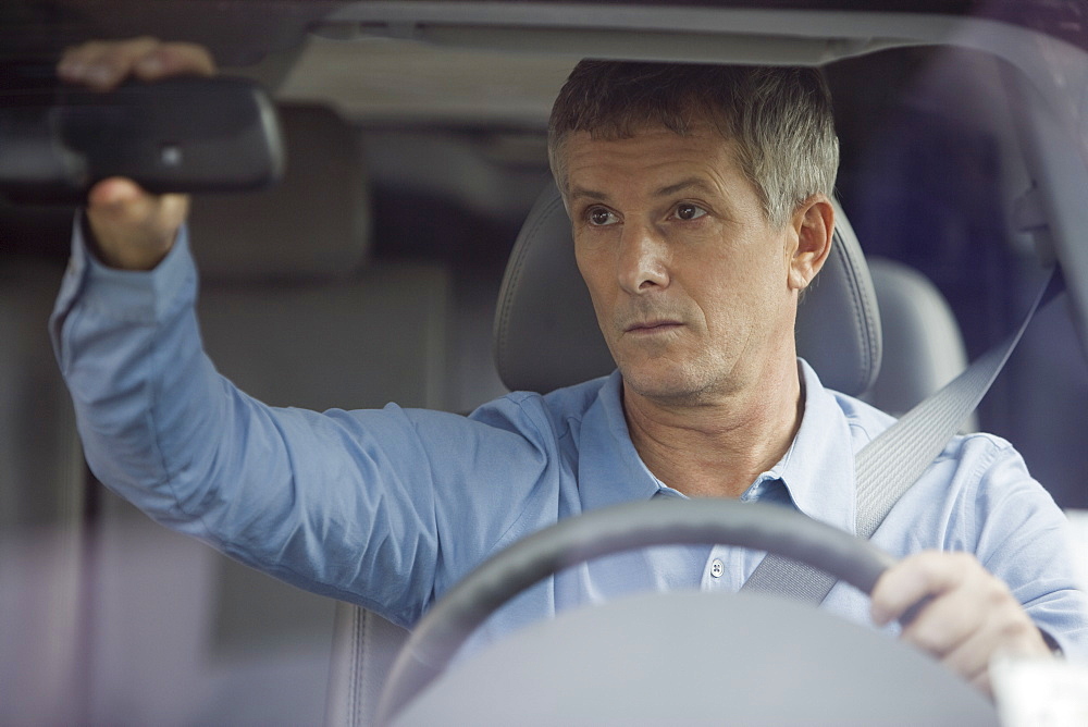 Man adjusting car rear view mirror