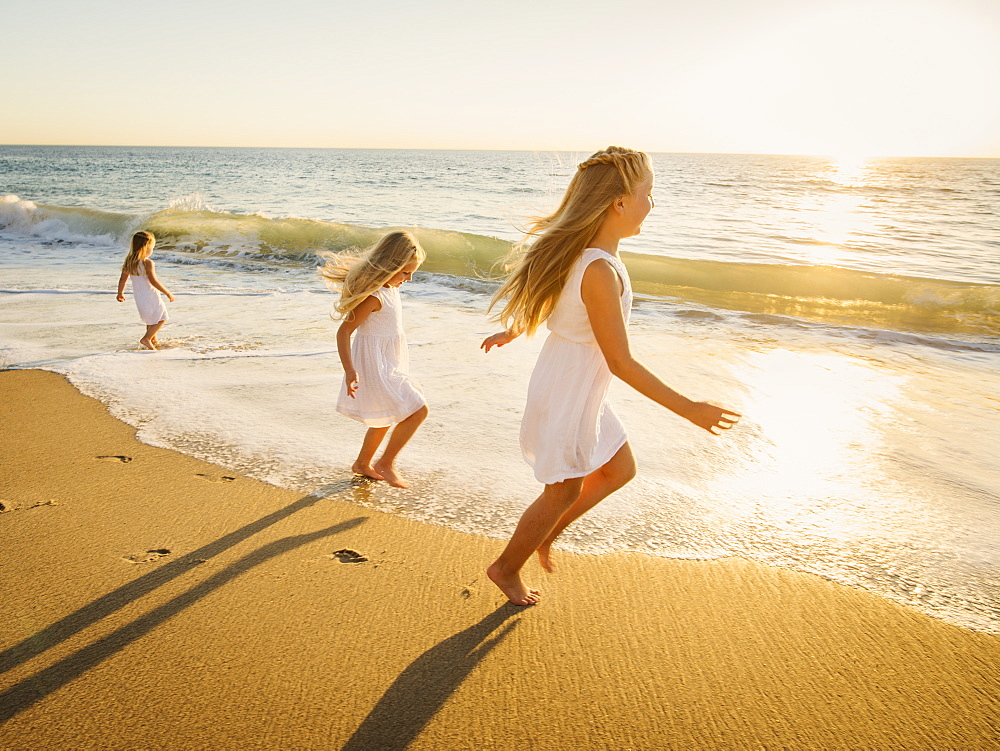 Girls (4-5, 6-7, 8-9) running on beach