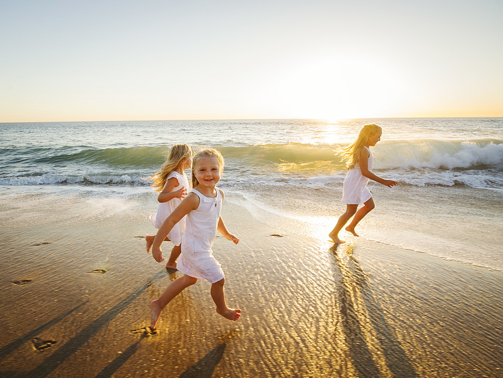 Girls (4-5, 6-7, 8-9) running on beach