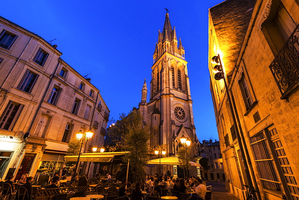 France, Occitanie, Montpellier, Sidewalk cafe and St. Anne Church at dusk