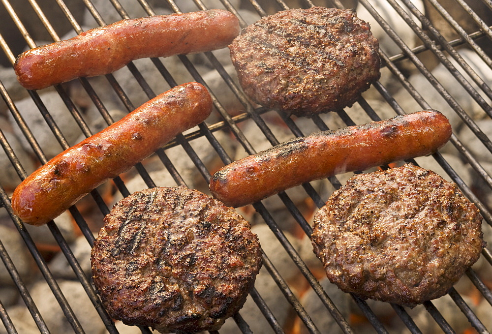 Hot dogs and hamburgers cooking on grill