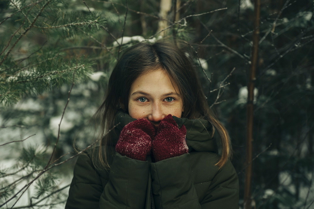 Teenage girl amongst pine branches in winter