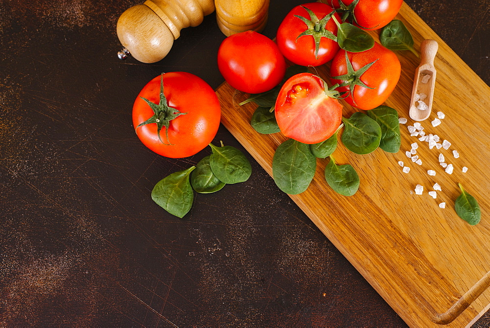 Tomatoes, basil and salt on wooden cutting board