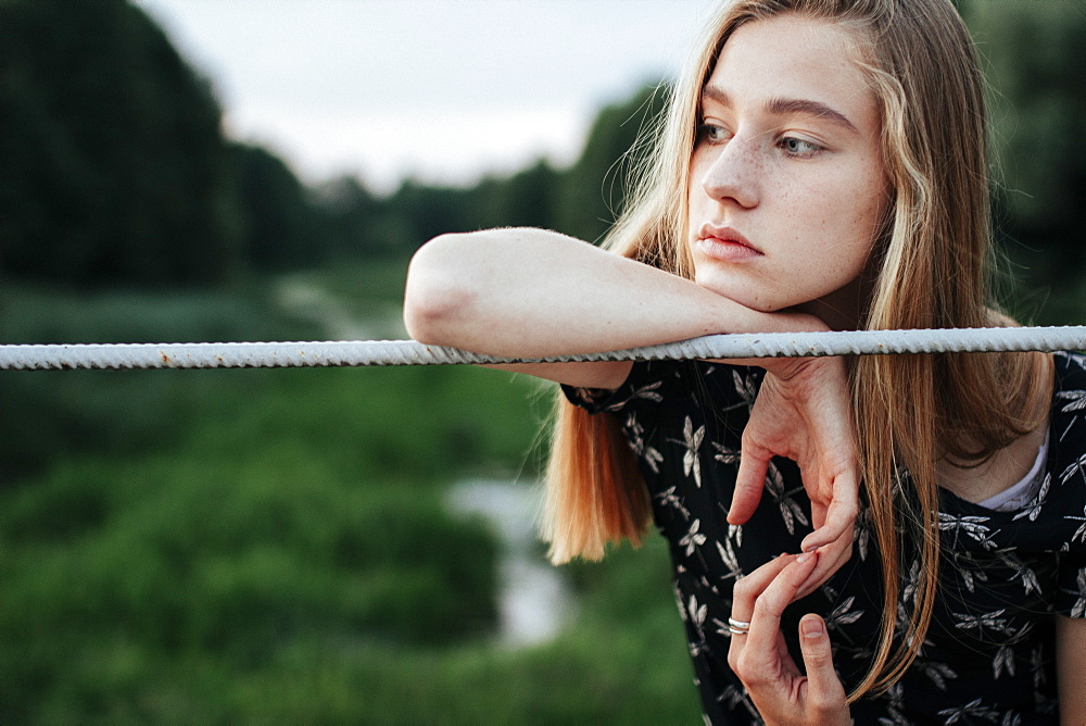 Young woman leaning on metal fence