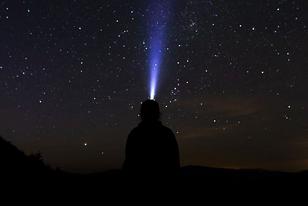 Silhouette of man with headlamp at night