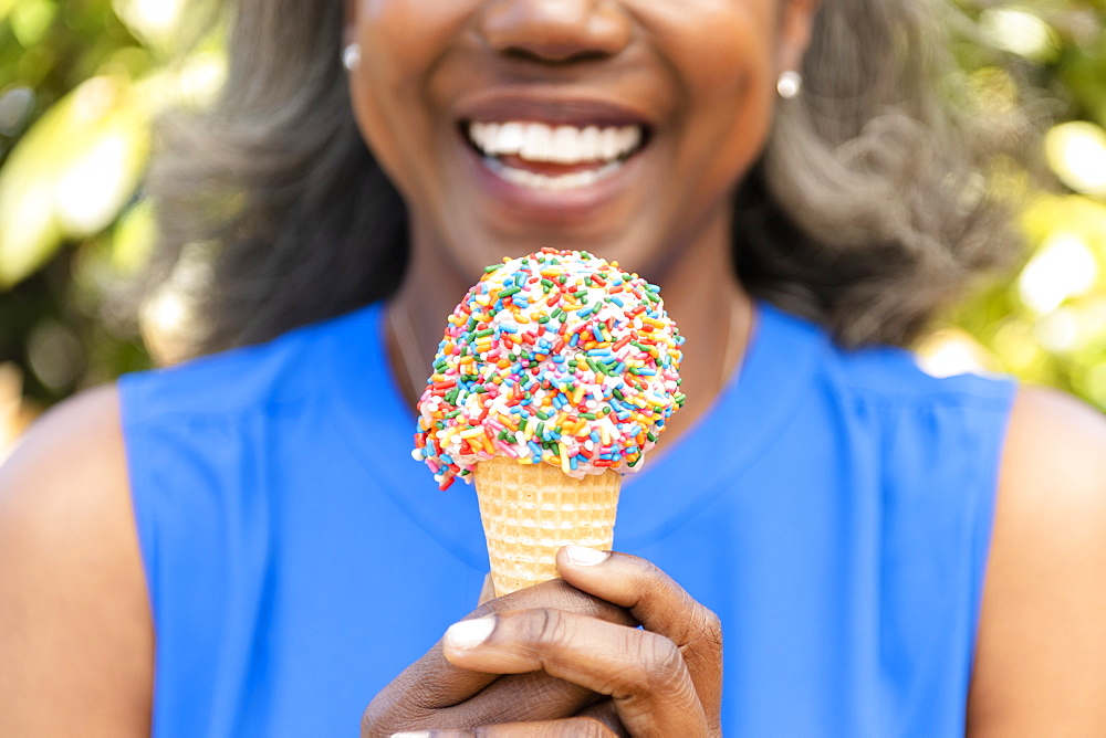 Mature woman holding ice cream cone with sprinkles