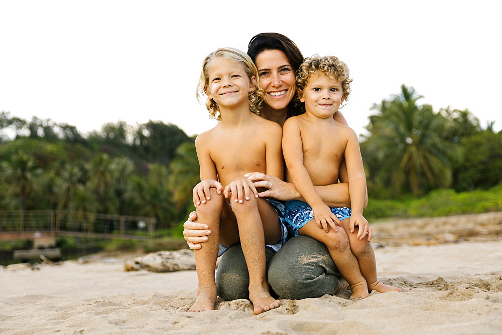 Woman with her sons sitting on her lap on beach