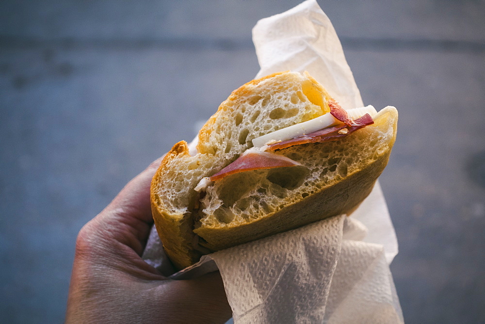 Woman's hand holding pancetta and cheese sandwich