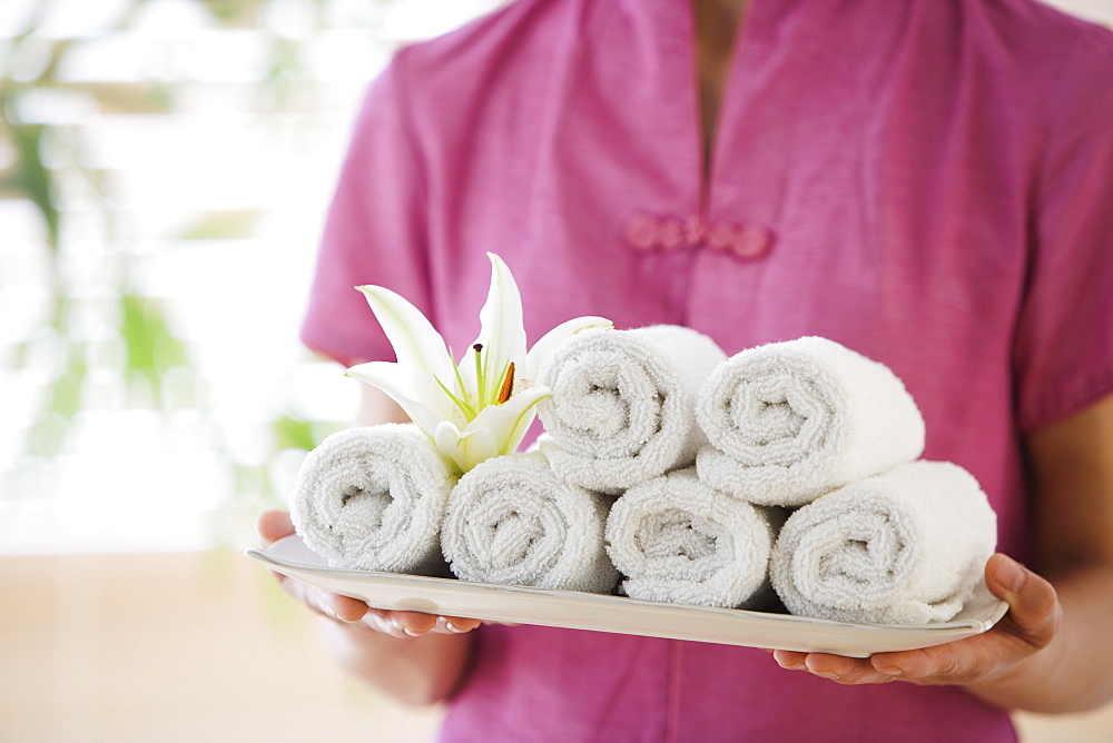 Woman holding tray of rolled towels