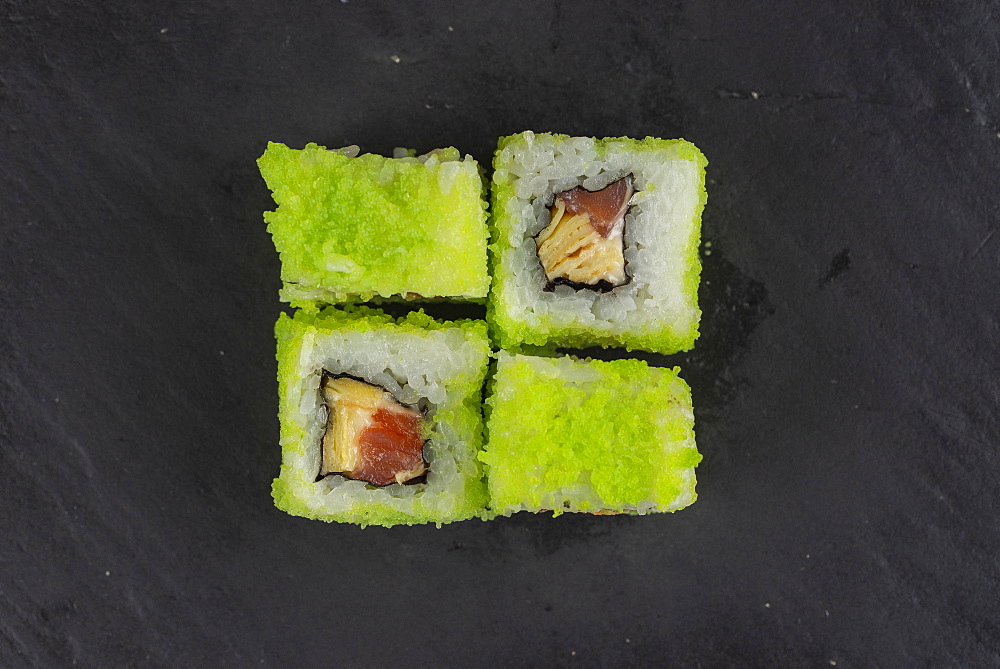 Green fish roe sushi on black surface