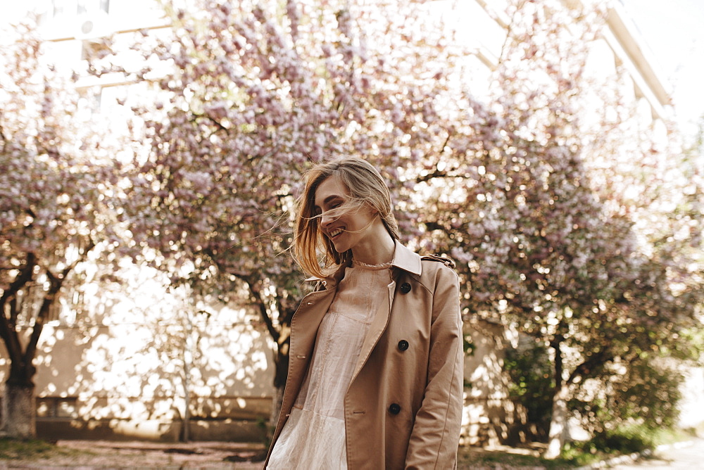 Smiling young woman by blossoming trees