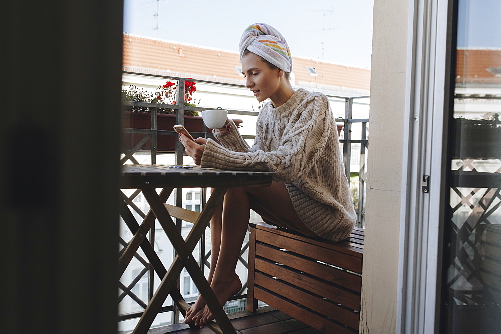 Young woman drinking coffee on apartment balcony