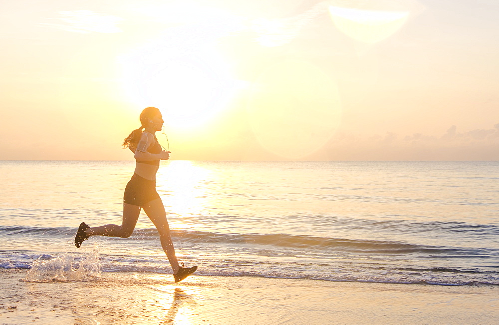 Woman jogging on beach at sunset