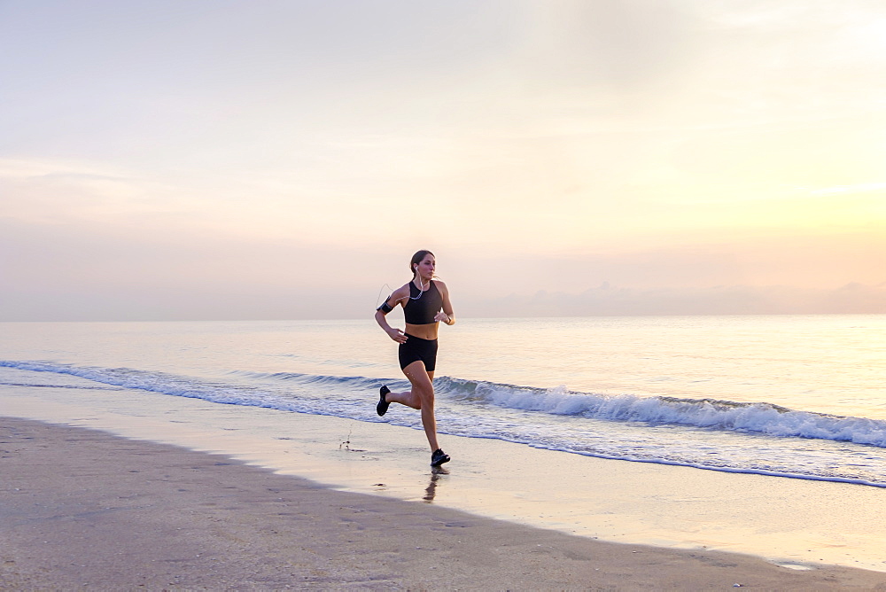 Woman jogging on beach at sunset