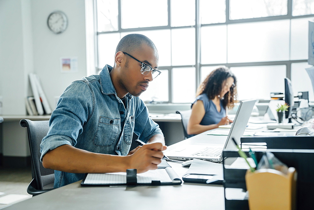 Man holding pen using laptop in office