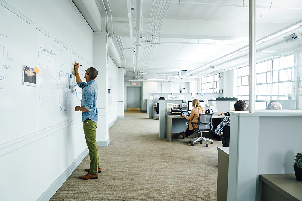 Man writing on whiteboard in office