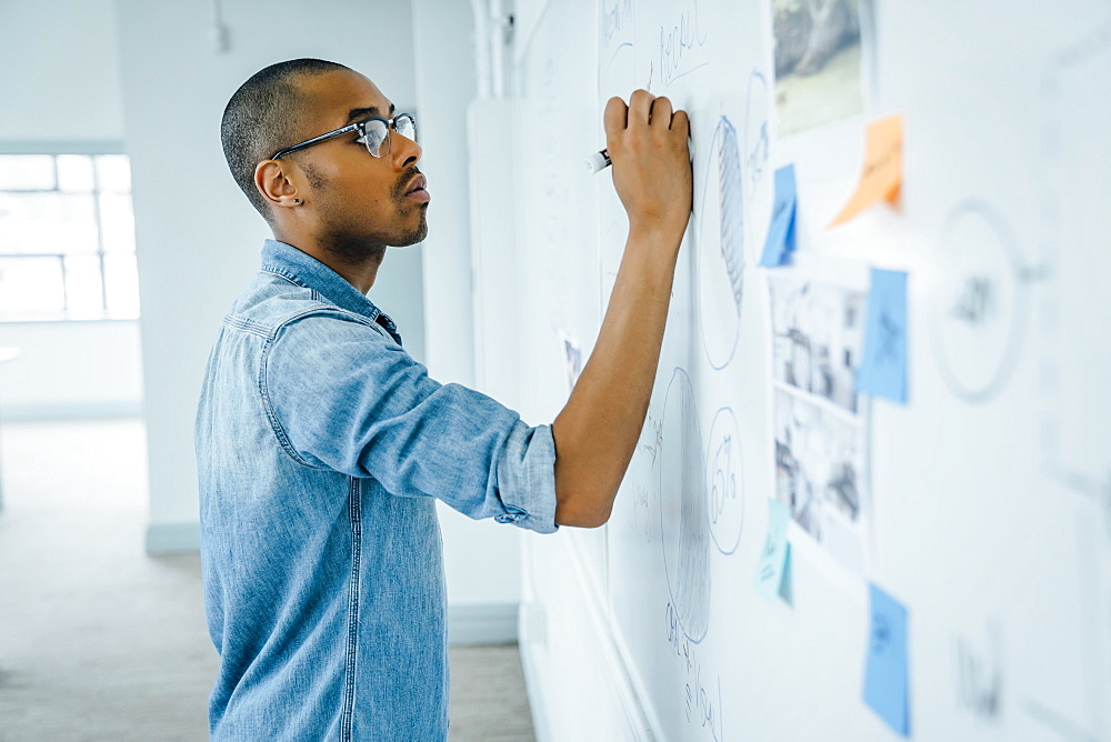 Man writing on whiteboard in office