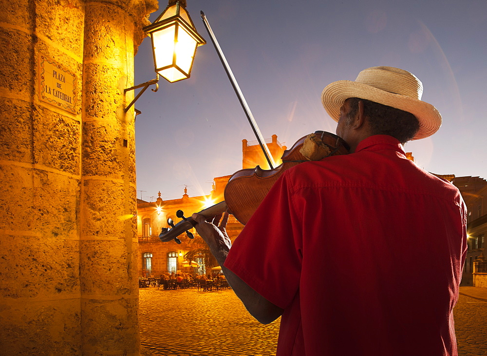 Senior man playing violin at night in Plaza de la Catedral, Havana, Cuba