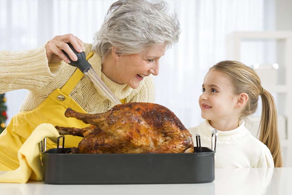 Grandmother and daughter basting roast turkey