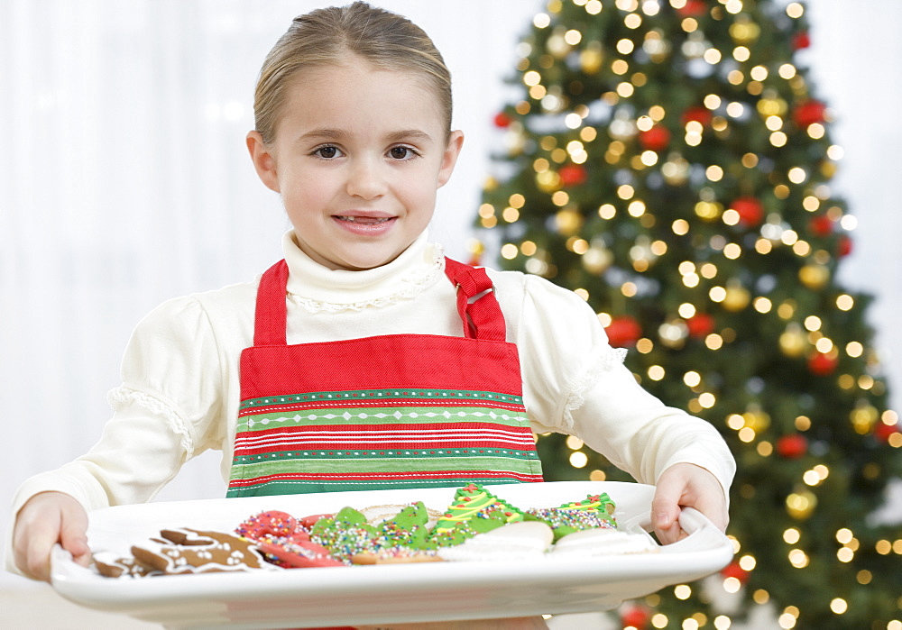 Girl carrying tray of Christmas cookies