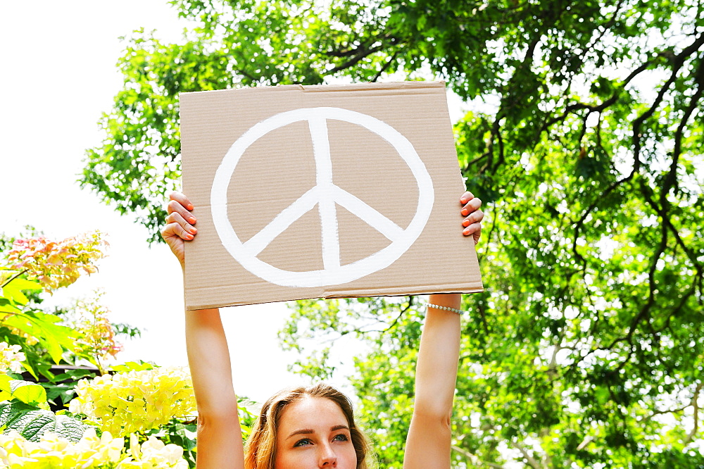 Young woman holding aloft peace symbol