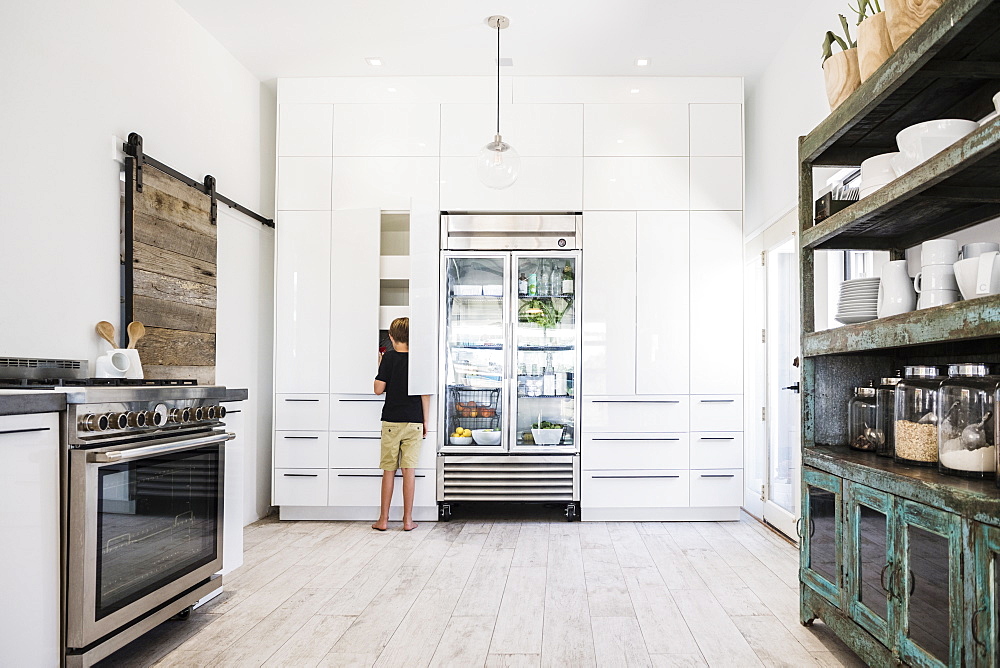 Boy looking in cupboard in kitchen