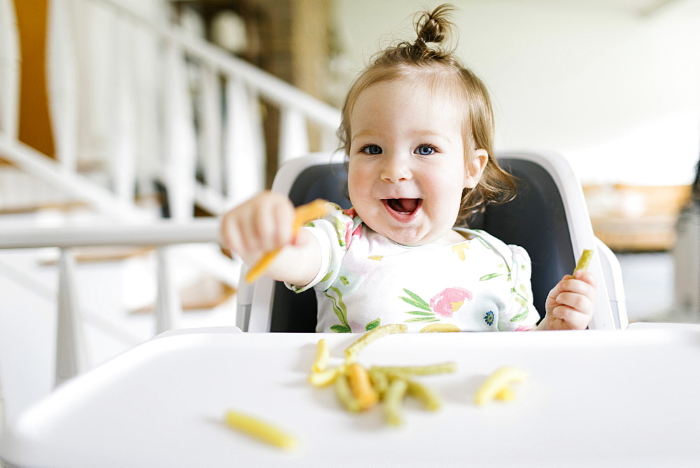 Baby girl eating in high chair