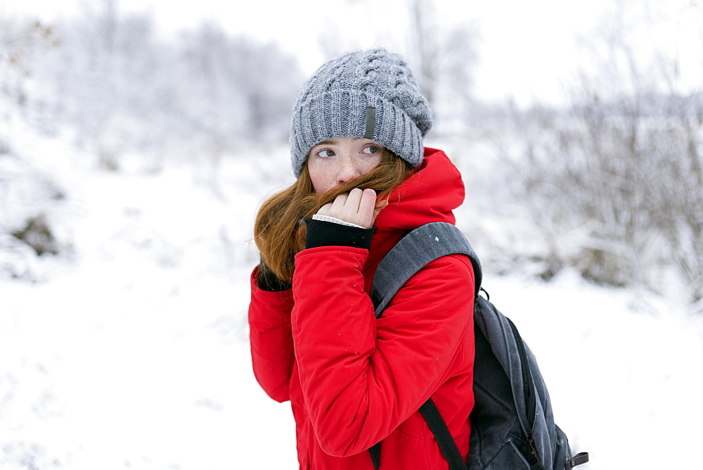 Teenage girl wearing red coat and grey hat in snow