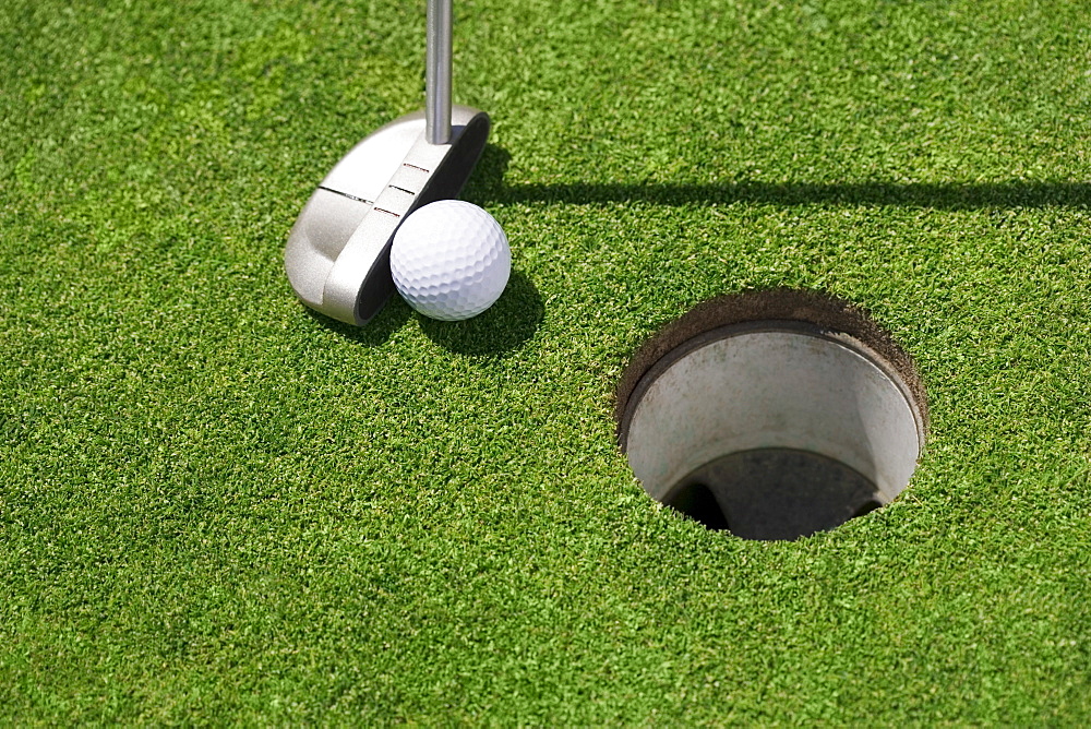 Golf ball near cup on putting green outdoors