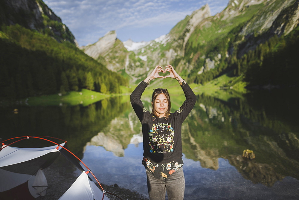 Woman making heart hand sign by Seealpsee lake in Appenzell Alps, Switzerland