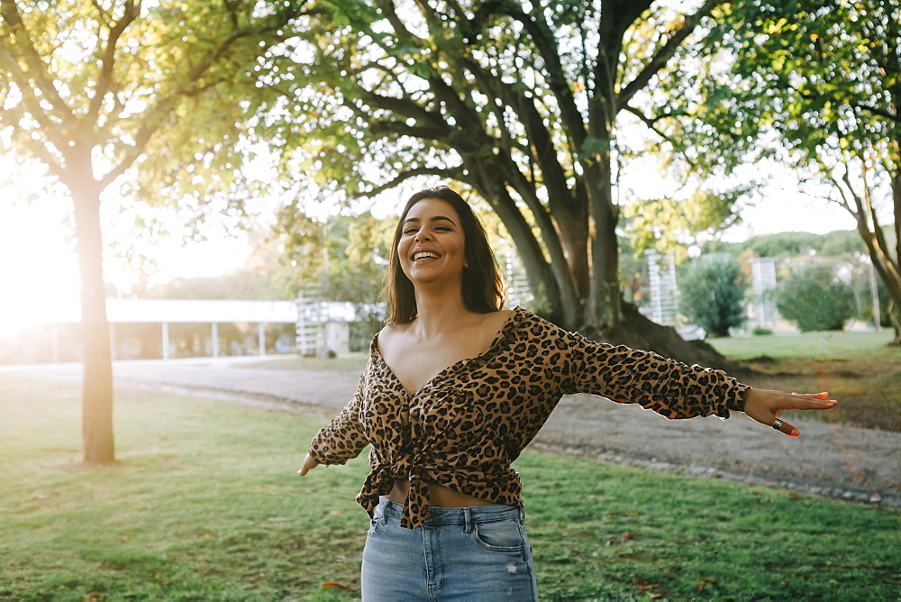 Smiling woman with her arms outstretched in park, Lisboa, Lisbon, Portugal