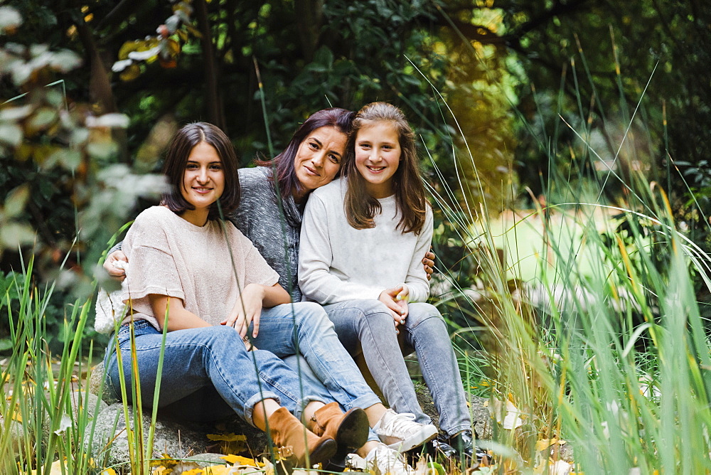 Mother and daughters embracing on grass