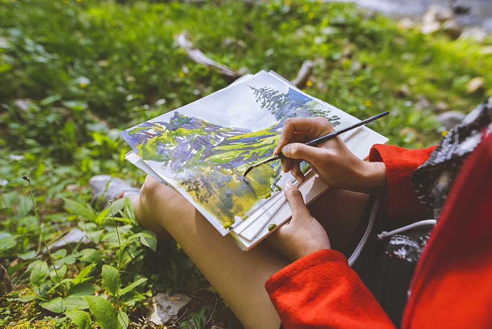 Woman painting with watercolors on grass